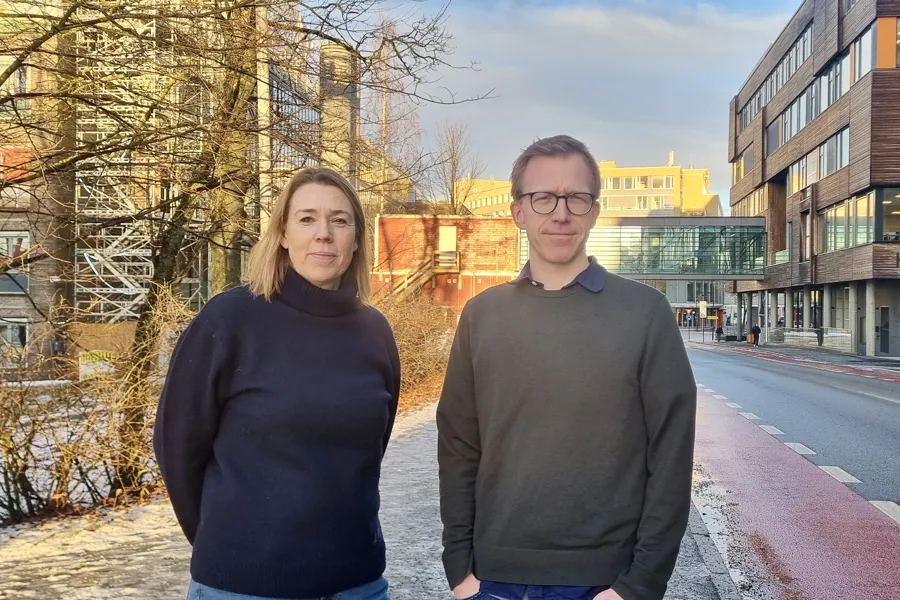 En mann og en kvinne står i en gate med bygninger på hver side