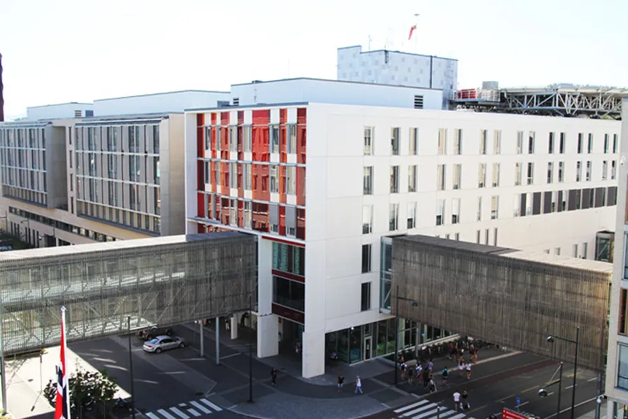 En stor hvit bygning med en gate og folk som gikk rundt