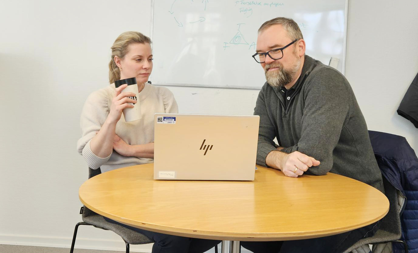 En mann og en kvinne som sitter ved et bord med en bærbar PC