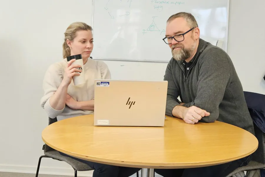 En mann og en kvinne som sitter ved et bord med en bærbar PC