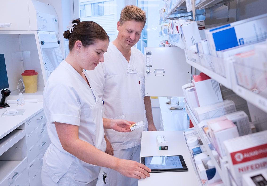 En mann og en kvinne i hvit laboratoriefrakk som ser på et nettbrett