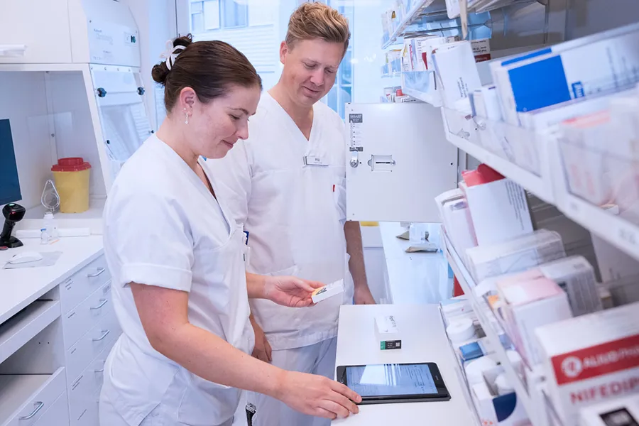 En mann og en kvinne i hvit laboratoriefrakk som ser på et nettbrett