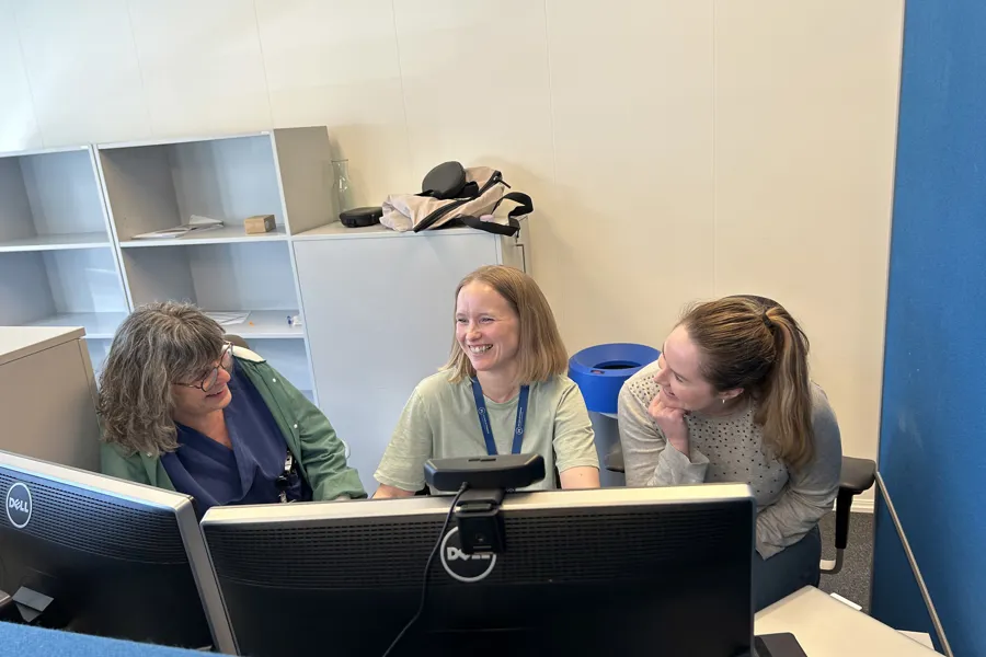 En gruppe mennesker som sitter ved et bord med datamaskiner