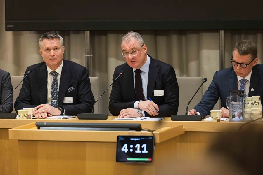 En gruppe menn som sitter ved et bord med mikrofoner