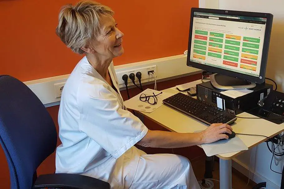 En person som sitter ved et skrivebord med en datamaskin