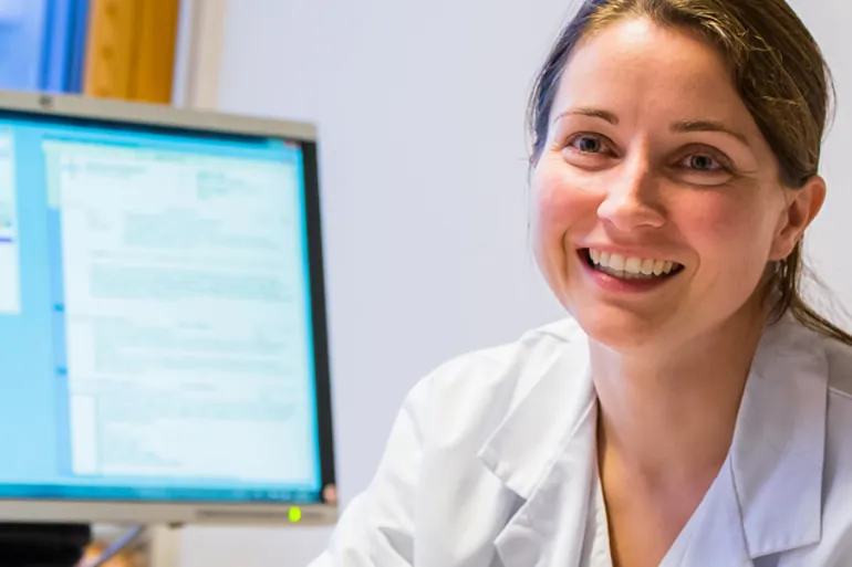 En kvinne som smiler foran en datamaskin