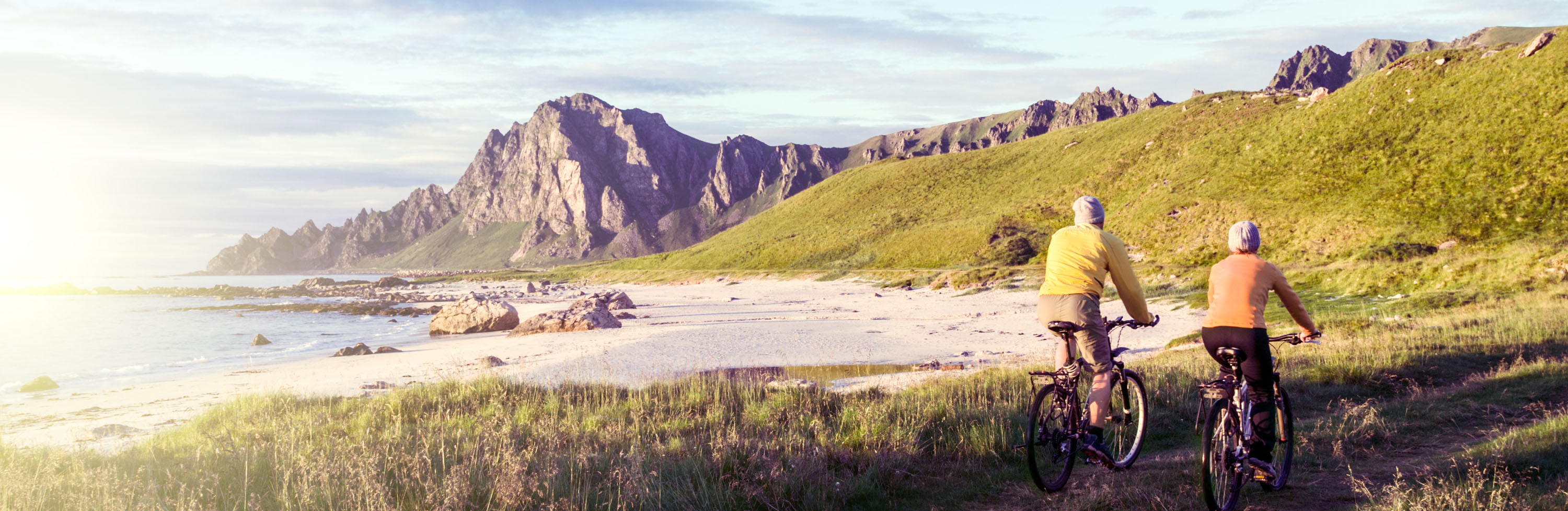 To personer som sykler på en sti nær en strand