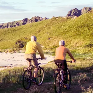 To personer som sykler på en sti nær en strand