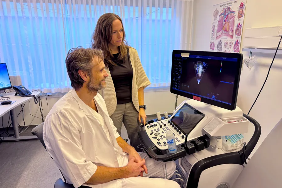 En kvinne som viser en mann noe på datamaskinen