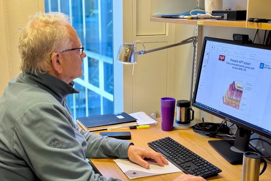 En mann som sitter ved et skrivebord og bruker en datamaskin