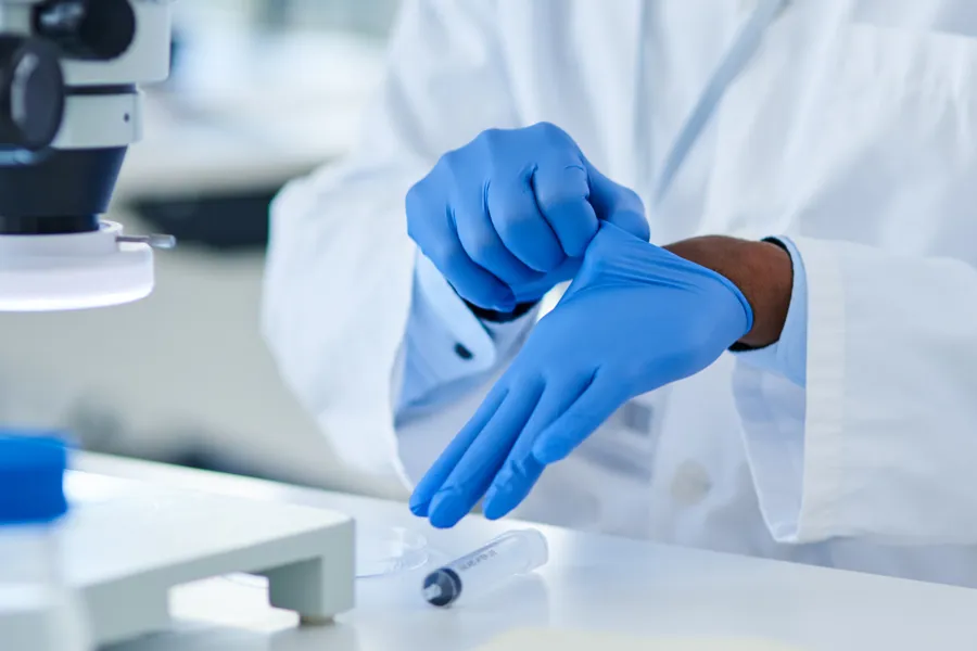 En person som har på seg hansker og blå hanske