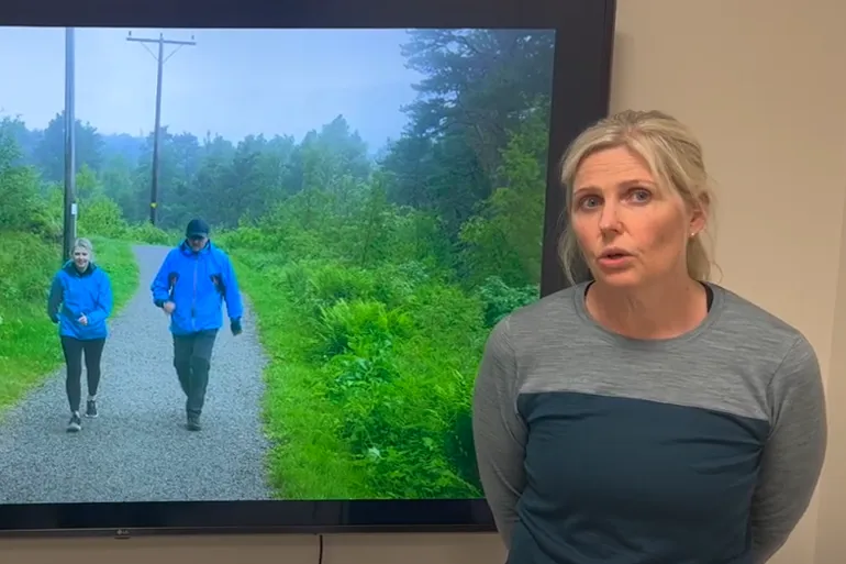 En kvinne som ser på en mann som går på en sti med trær og gress