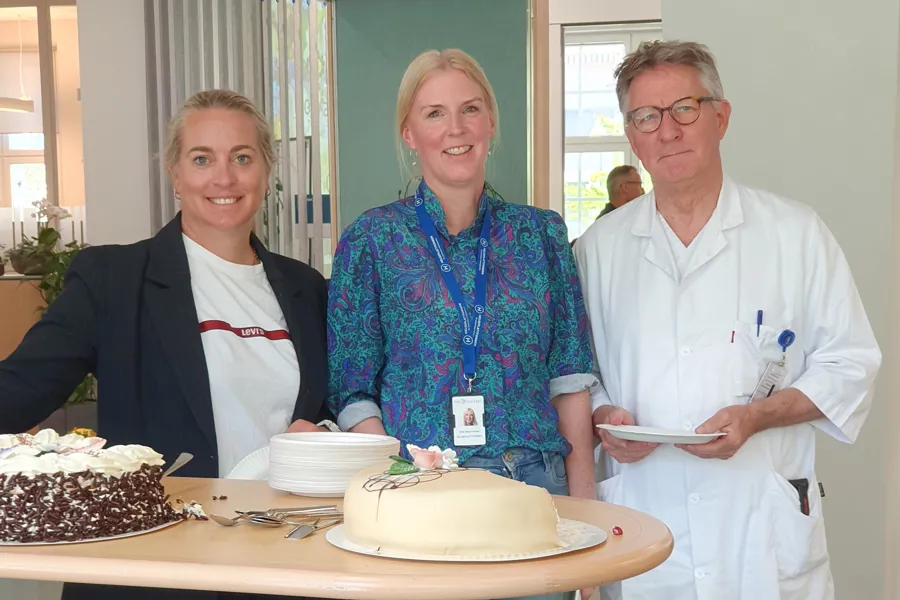 En gruppe mennesker står rundt et bord med en kake
