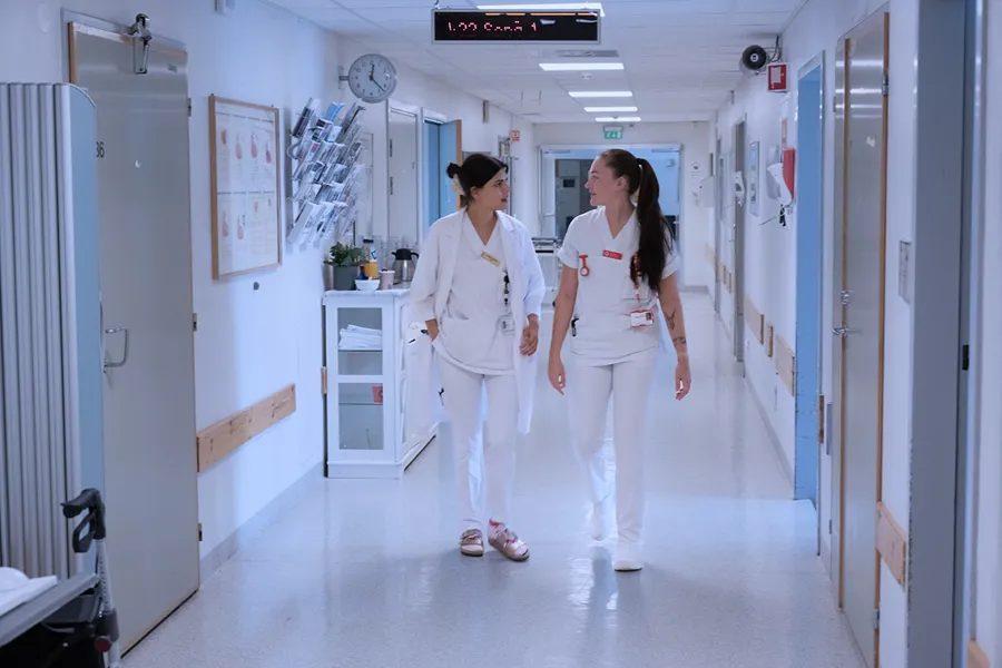 Et par kvinner i hvite laboratoriefrakker som går i en gang