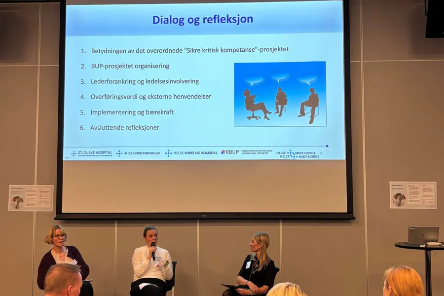 En gruppe mennesker som sitter foran en projektorskjerm