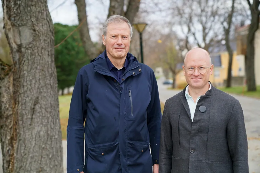 A couple of men standing next to a tree