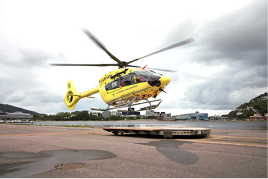 Et gult helikopter som flyr over en rullebane